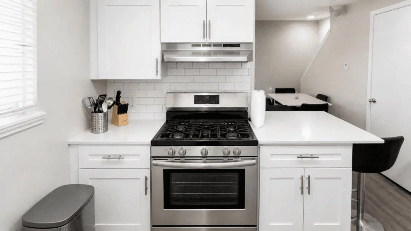 A modern kitchen with white cabinets, a stainless steel stove, and a countertop.