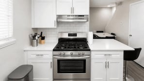 A modern kitchen with white cabinets, a stainless steel stove, and a countertop.