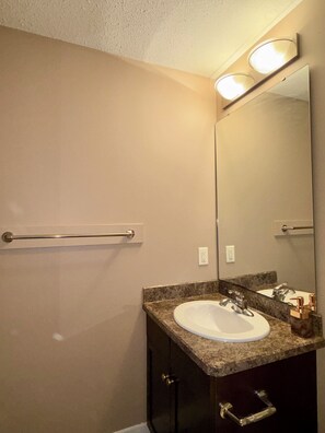 A bathroom with a white sink, a mirror, and a towel rack. - Modern & Cozy 2BR | Near Refinery, Airport & Central Regina (Regina)