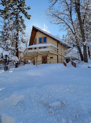 Un bâtiment à deux étages doté d’un balcon, entouré d’arbres couverts de neige.