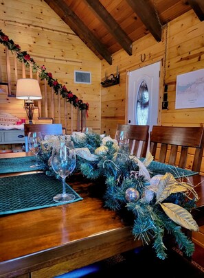A wooden interior with a table set for dining, decorated with greenery and ornaments. - Cozy Big Bear Cabin • Sleeps 10 • Pet Friendly! (Big Bear)