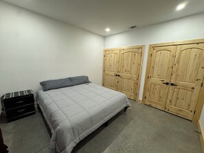A bedroom with a bed, two wardrobes, a dresser, and a carpeted floor. - New horse property  3 bed duplex with central heat and air near Stephenville (Stephenville)