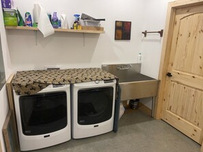 A laundry room with two front-loading washing machines, a sink, and a wooden door. - New horse property  3 bed duplex with central heat and air near Stephenville (Stephenville)