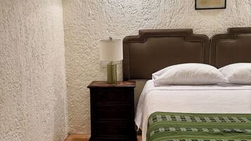 A bedroom with a bed, a nightstand, a lamp, and a wall-mounted light fixture.