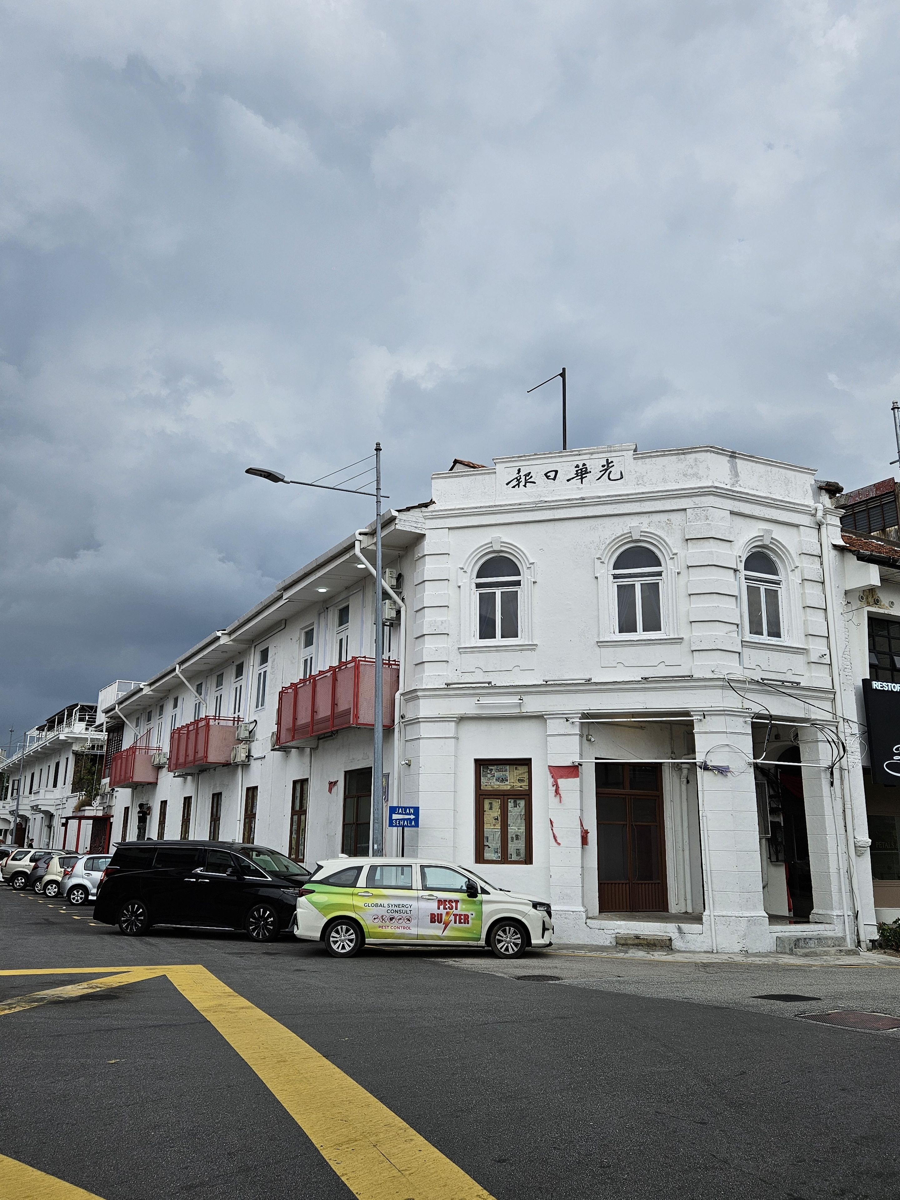 Ein weißes Gebäude mit einem Schild, auf dem 'Jalan Senai' steht, und ein geparktes Fahrzeug davor.