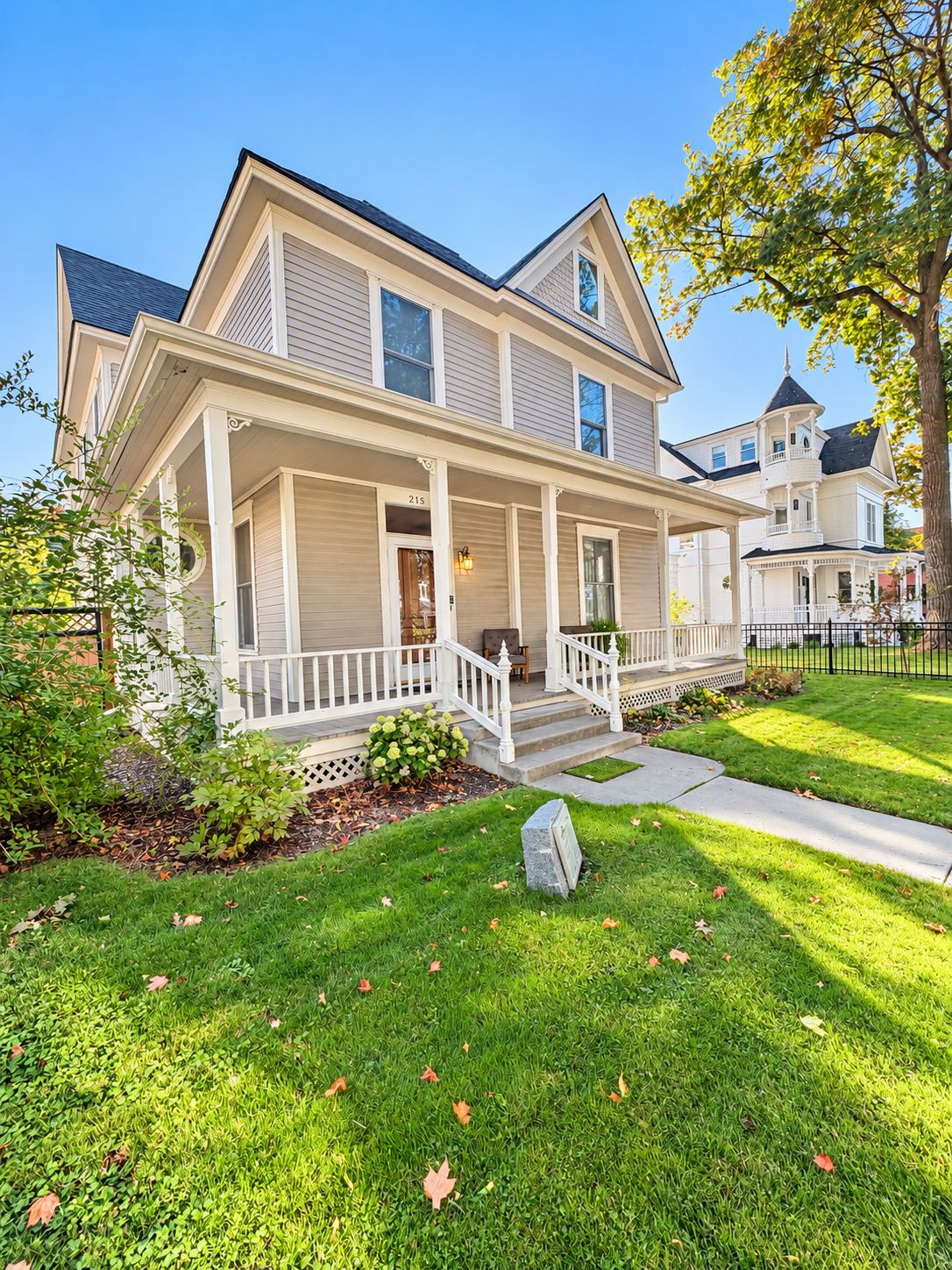 A two-story house with a front porch, a visible address number, and a well-maintained lawn.