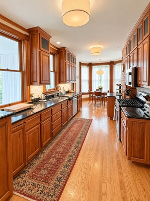 A spacious kitchen with wooden cabinetry, a central island, and a dining area with a table and chairs. - Historic 4BR and 3 Bath, University District Home, Sleeps 8, Near UM & Downtown (Missoula)
