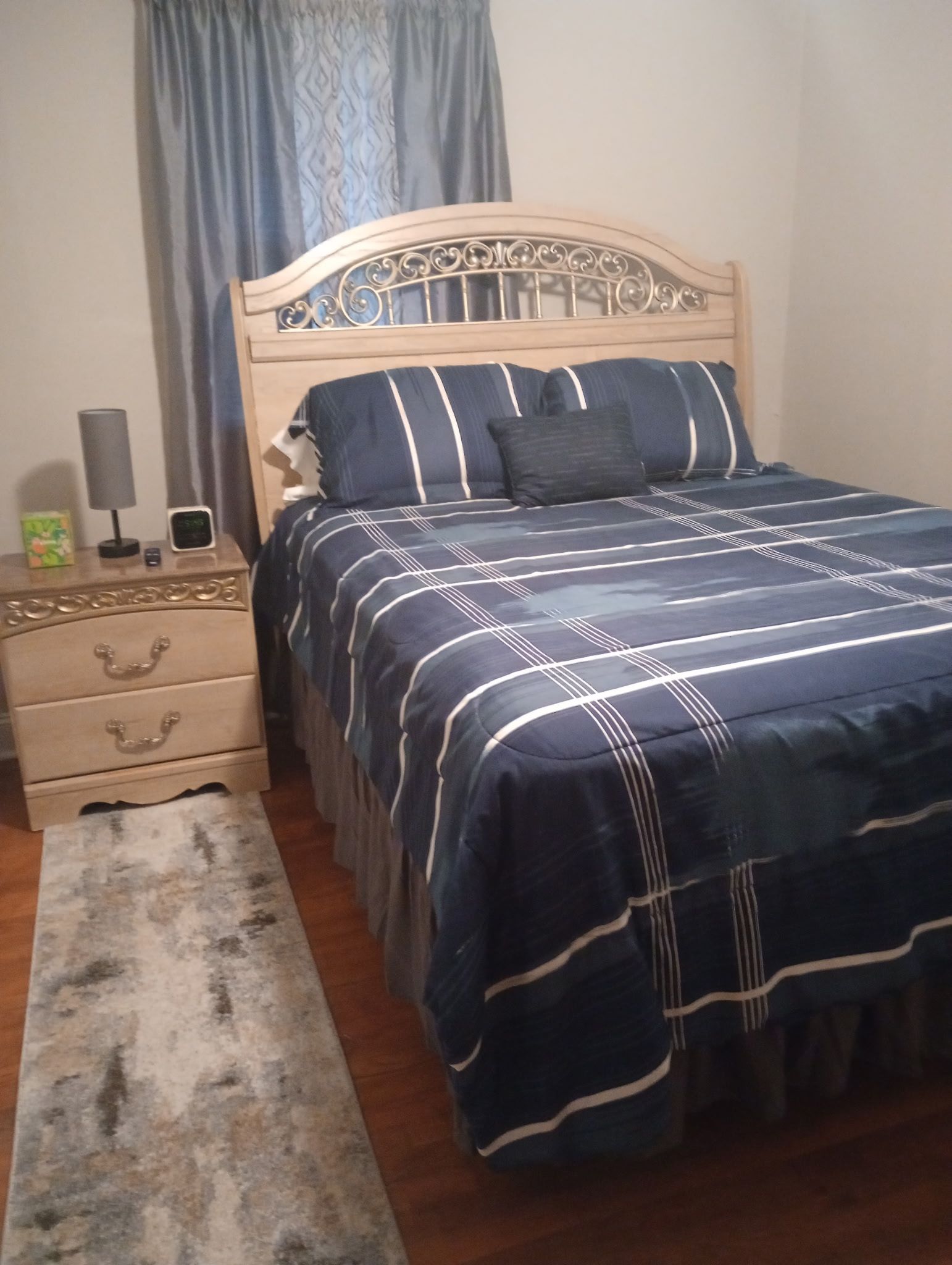 Une chambre à coucher avec un lit, une table de chevet, une lampe et un tapis.