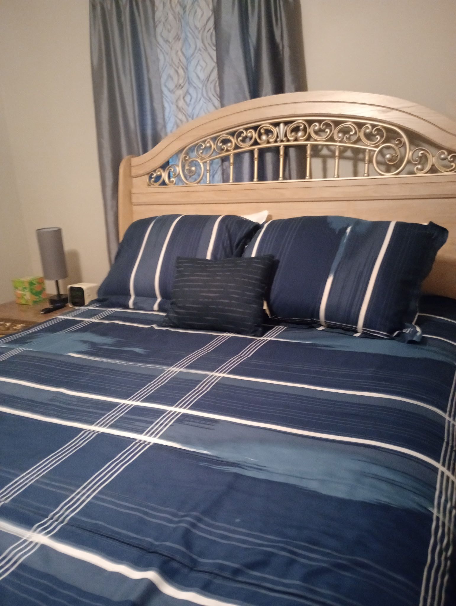 Un letto con testiera, una coperta a righe blu e bianche e due cuscini.
