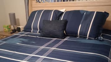 Un letto con testiera, una coperta a righe blu e bianche e due cuscini.