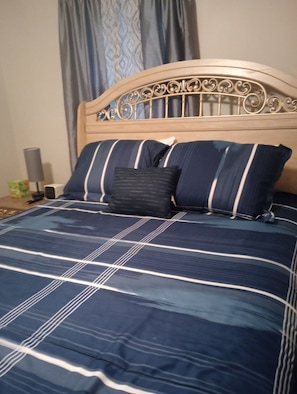 Un letto con testiera, una coperta a righe blu e bianche e due cuscini.