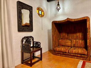 A room with a wooden sofa, a small table with a decorative item, a mirror, and a wall-mounted light fixture. - Up to 15 bedroom house in Cuernavaca perfect for large groups (Cuernavaca)