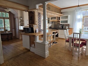A spacious kitchen with wooden flooring, a central island, and a dining area with white chairs.