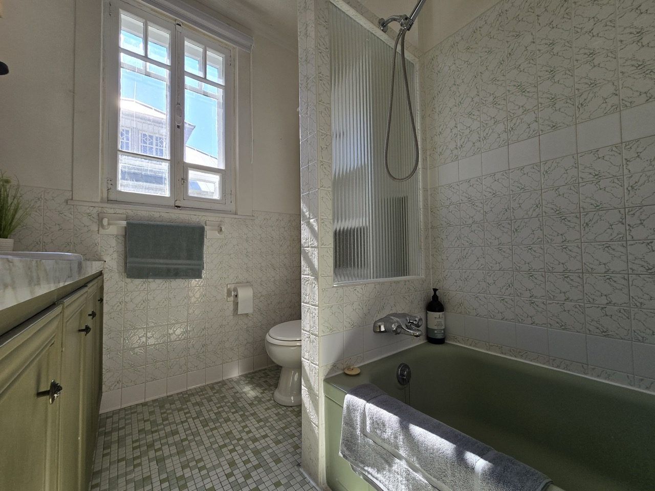 A bathroom with a toilet, a bathtub, a window, and a sink.