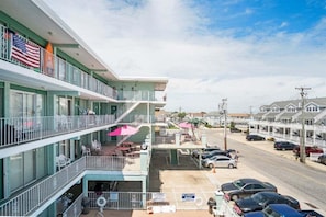 Een hotel met meerdere verdiepingen, voorzien van balkons, terras en een parkeerplaats.