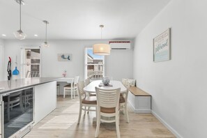 A modern kitchen with a dining area, white walls, and a large window. - The Sunflower Beach Club by Experience Vacation Rentals (Wildwood)