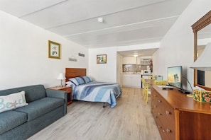 A compact room with a bed, a sofa, a desk, and a kitchenette. - The Sunflower Beach Club by Experience Vacation Rentals (Wildwood)