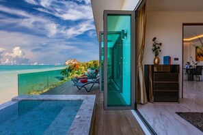 Un interior moderno con un ventanal de vidrio que da a un balcón con vistas a la playa y al océano.