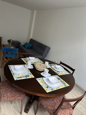 A dining table set with white plates, cups, and cutlery, surrounded by chairs with red and brown upholstery. - New Listing (Bogotá)