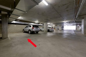 A multi-level parking garage with concrete pillars and overhead lighting. - Designer Living in Historic Art Deco (Hobart)
