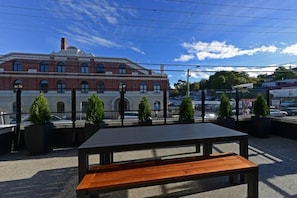 A rooftop terrace with a wooden table and potted plants. - Designer Living in Historic Art Deco (Hobart)