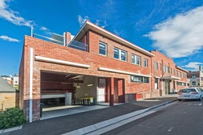 A two-story building with a garage entrance, a sign indicating a dental office, and a clear blue sky. - Designer Living in Historic Art Deco (Hobart)
