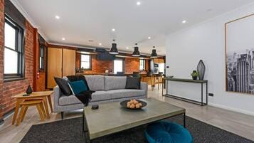 A modern living room with a sofa, coffee table, and a cityscape painting.