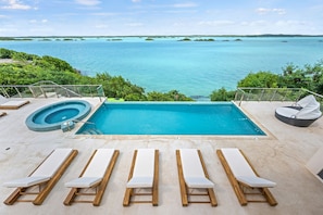A swimming pool with a view of the ocean, surrounded by lounge chairs and a hot tub. - Alta Bella Villa 8 Bdr Oceanfront Nordic Spa (Providenciales)