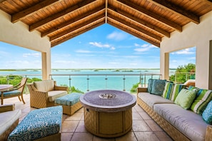 A covered outdoor seating area with a view of a calm body of water and distant islands. - Alta Bella Villa 8 Bdr Oceanfront Nordic Spa (Providenciales)