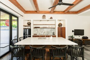 Eine moderne Küche mit Marmorarbeitsplatte, Holzschränken und einem Essbereich mit großem Tisch und Stühlen.