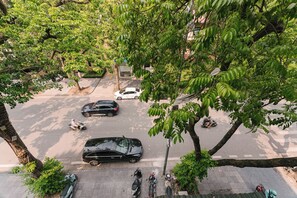 A street view with parked cars, a pedestrian crossing, and trees. - OH Trendy homes Hoan Kiem LTT - City view duplex (Cua Nam)