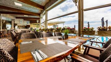 A restaurant with a wooden interior, large windows, and outdoor seating with umbrellas.