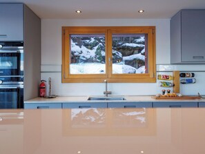 Eine moderne Küche mit einem großen Fenster, Edelstahlgeräten und einer Holzausziehtafel.