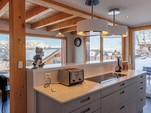 A kitchen with a wooden ceiling, a large window with a view of snow-covered mountains, a toaster, and a kettle on the counter. - Nice apartment in villa for 8 guests with WIFI, TV and terrace (Basse-nendaz)