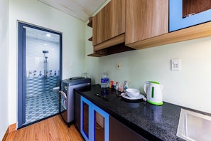 A compact kitchen with a built-in dishwasher, a coffee maker, and a water dispenser on the counter. - Comfortable Studio Kingbed Windows Mango Mango Apartments (Đà Nẵng)