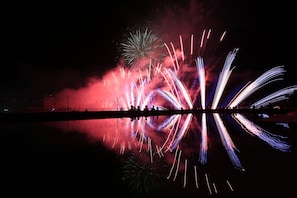 A nighttime view of a fireworks display over a body of water with reflections. - Comfortable Studio Kingbed Windows Mango Mango Apartments (Đà Nẵng)