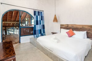 A bedroom with a large bed, a wooden headboard, a window with blue curtains, and a view of a wooden structure outside. - Flow House 3BR Beachside An Bang Beach Hoi An by Beachside Boutique Homes (Đà Nẵng)