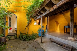 A courtyard with a yellow wall, wooden beams, a stone pathway, and potted plants. - Flow House 3BR Beachside An Bang Beach Hoi An by Beachside Boutique Homes (Đà Nẵng)