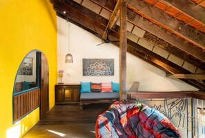 An interior with a high ceiling, exposed wooden beams, a colorful sofa, and a wall-mounted light fixture. - Flow House 3BR Beachside An Bang Beach Hoi An by Beachside Boutique Homes (Đà Nẵng)