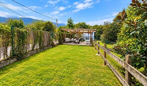 Un patio trasero con cerco de madera, pérgola y mobiliario exterior.