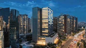 A high-rise hotel with a modern glass facade, surrounded by other tall buildings, and a busy street with cars.