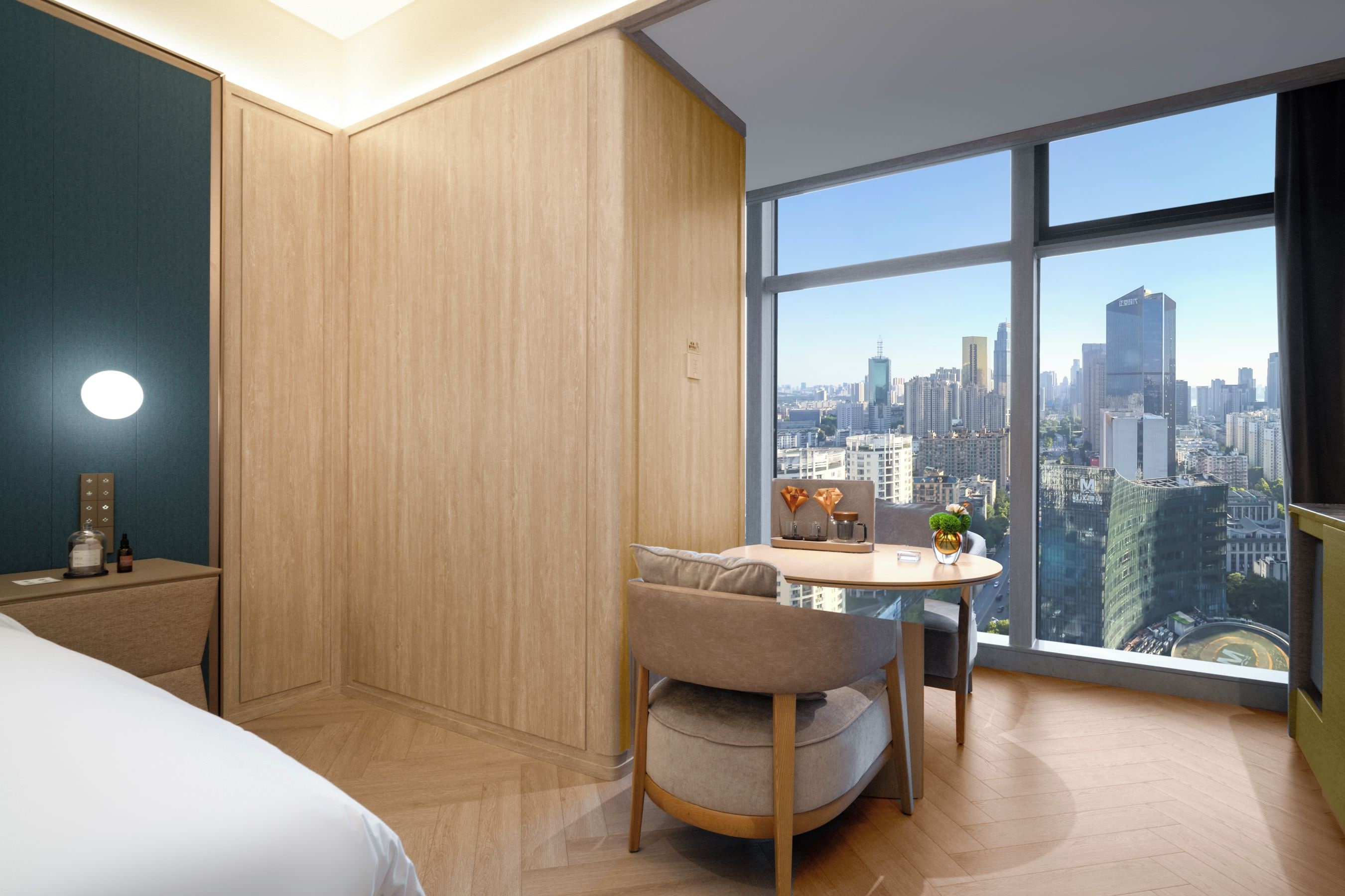 Habitación de hotel con vista a la ciudad, una cama, un escritorio y una pequeña mesa con una silla.