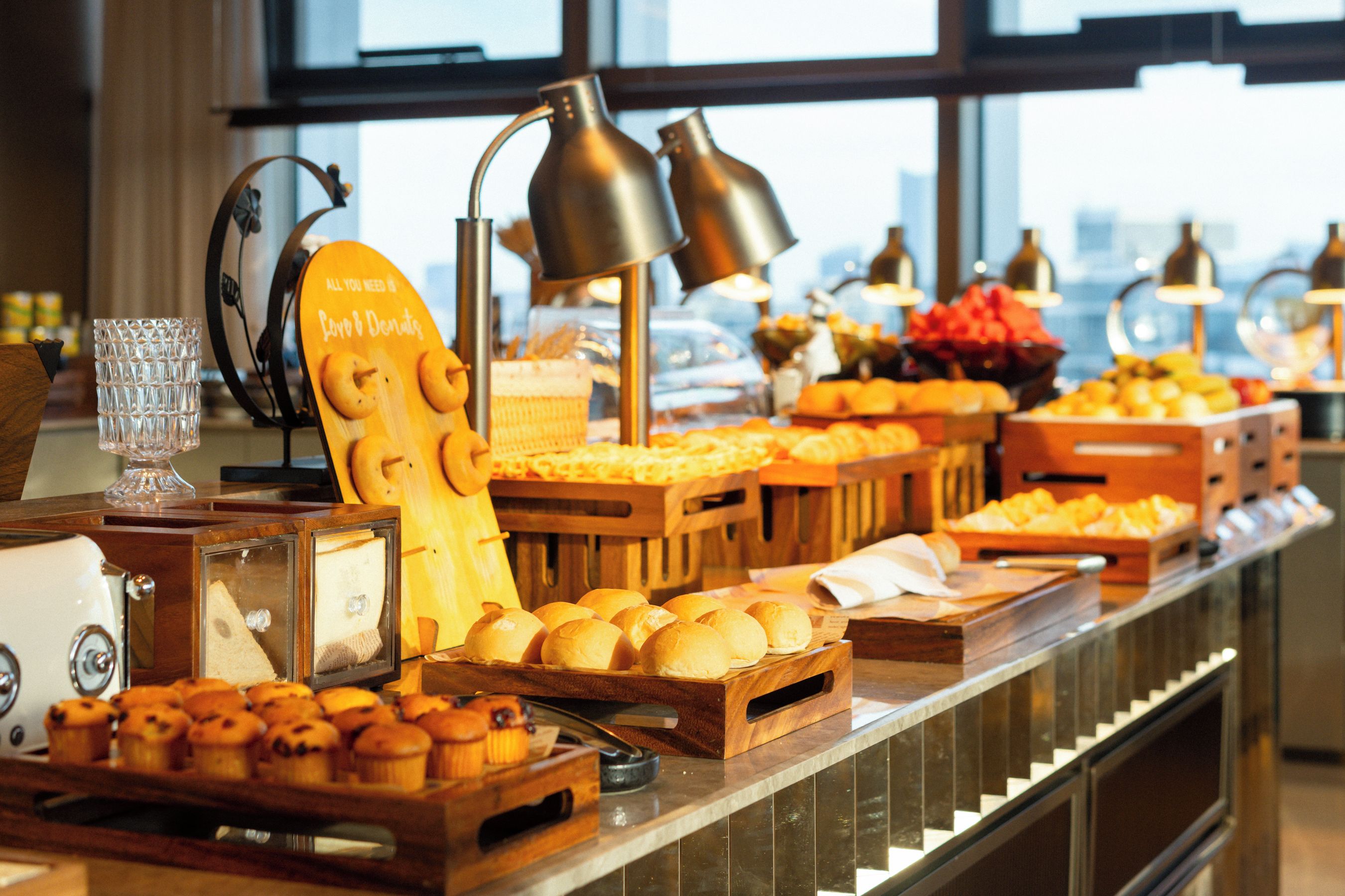 A buffet with various food items, including bread, muffins, and fruits.