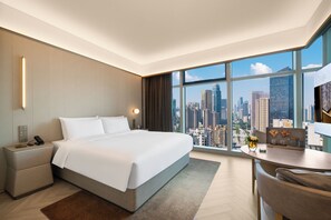 A modern hotel room with a large bed, a desk with a chair, and a view of a cityscape through large windows. - Crystal Orange Hotel (Wuhan)