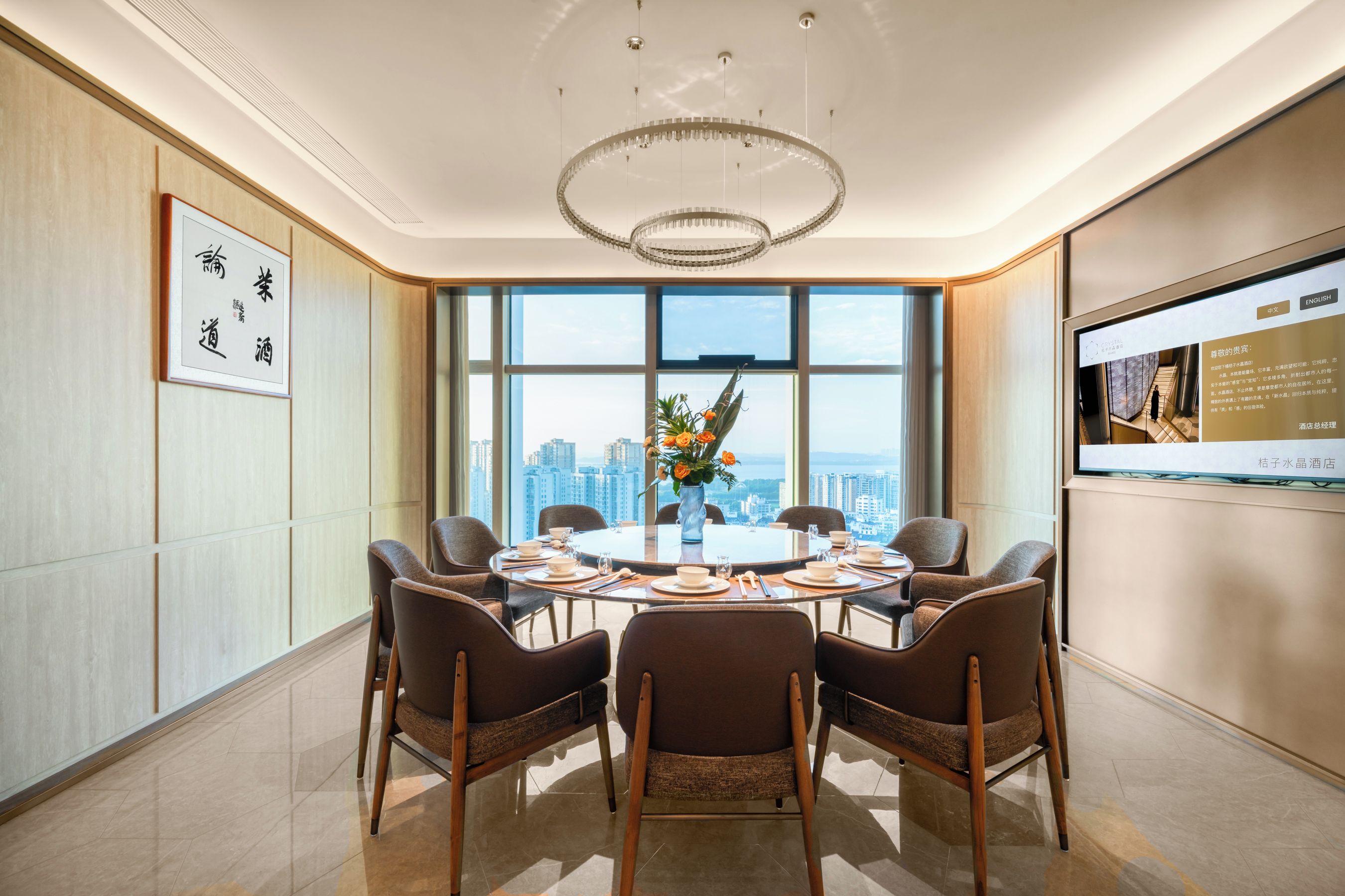 Una sala conferenze moderna con un tavolo rotondo, sedie, un lampadario e un'ampia finestra con vista sulla città.