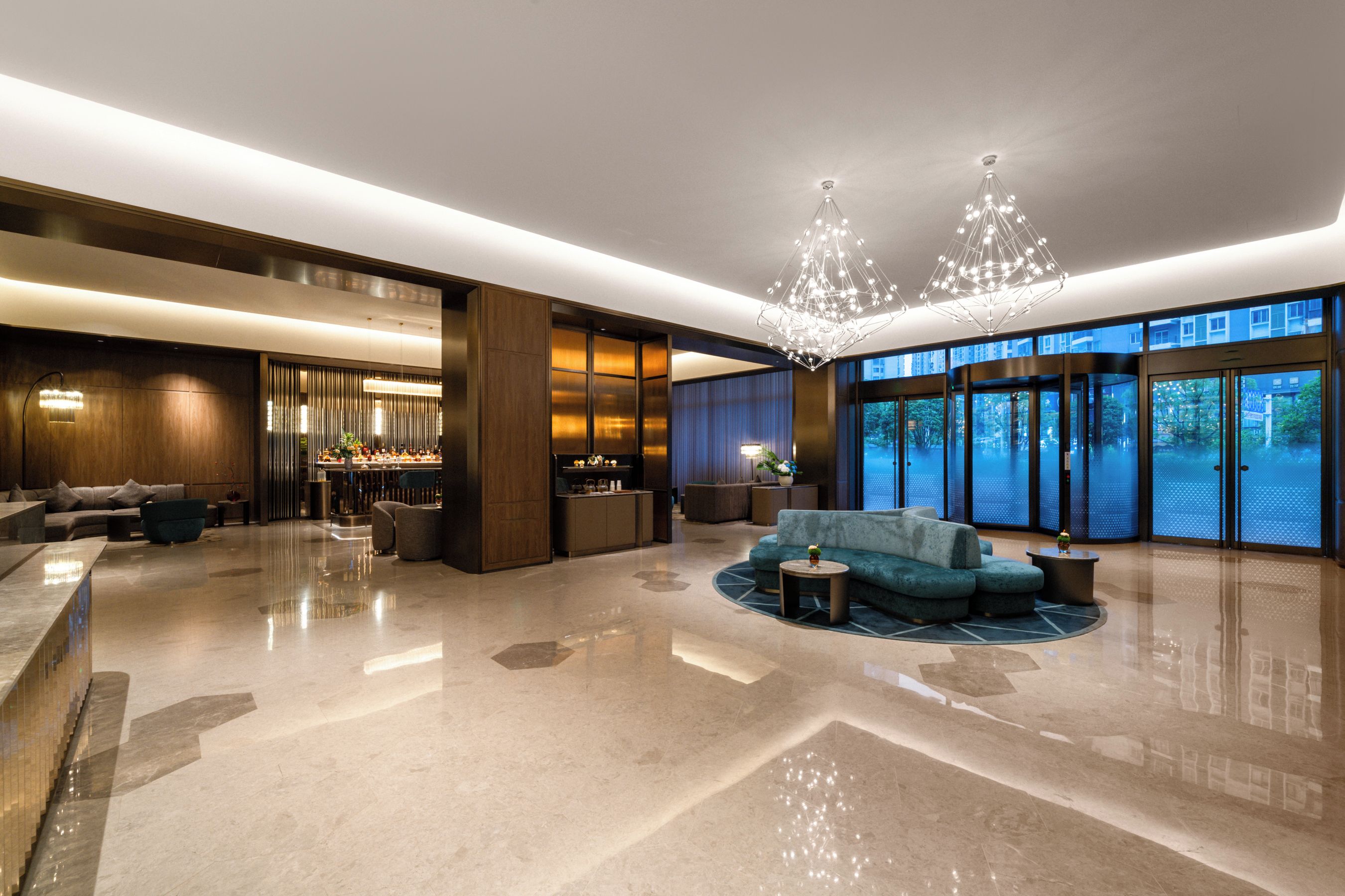 A spacious lobby with a bar area, seating arrangements, and a large window offering a view of the outside.