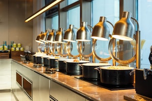 A buffet setup with multiple serving stations, each with a black pot and a metal lamp above. - Crystal Orange Hotel (Wuhan)