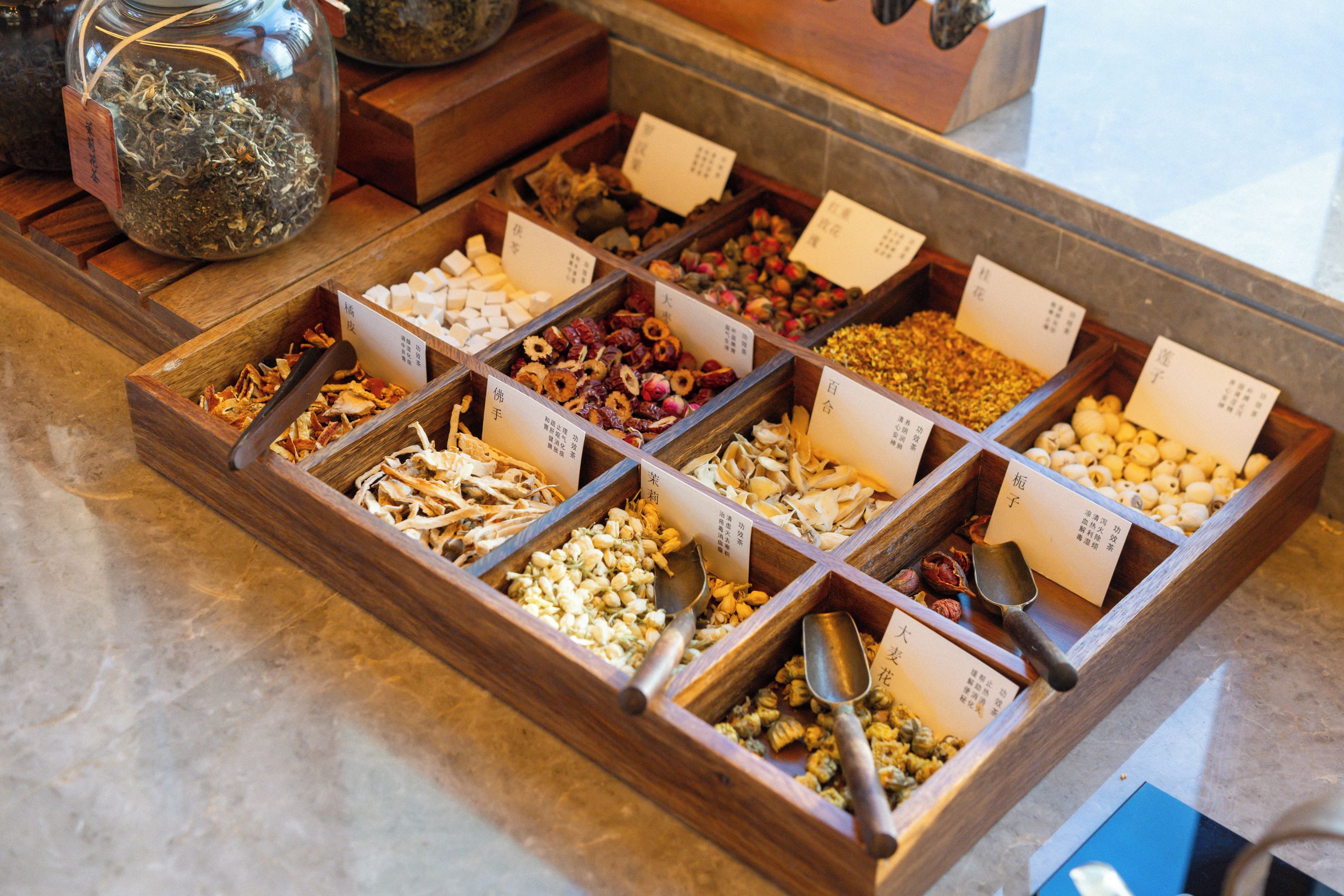 Una exhibición de diversos snacks secos y tés en cajas de madera con etiquetas.