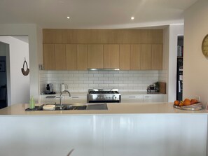 A modern kitchen with a central island, stainless steel appliances, and wooden cabinetry. - Your Comfortable, Spacious Phillip Island Getaway (Cowes)