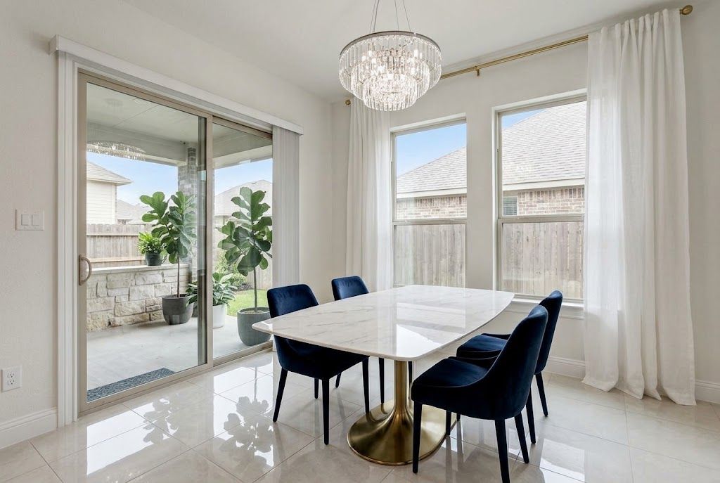 A dining area with a white marble table, blue chairs, and a chandelier.